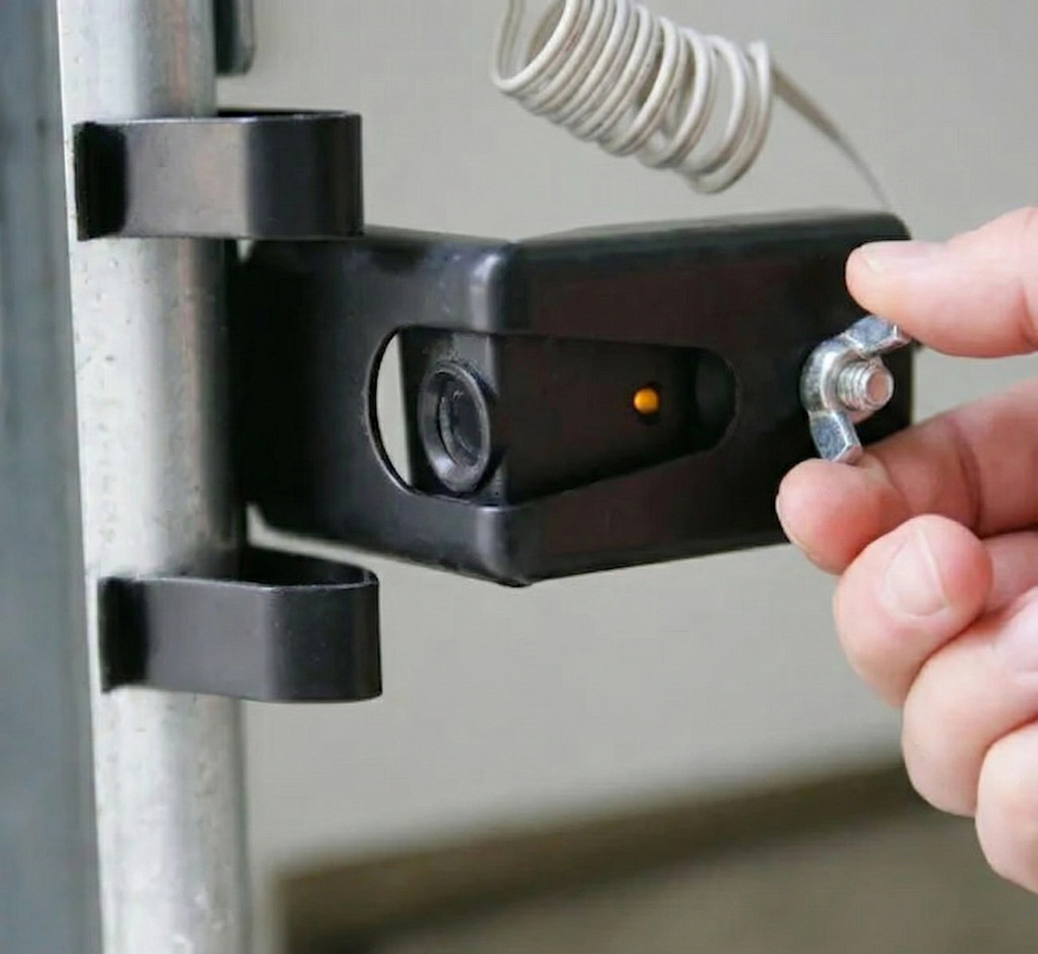 Adjusting garage door sensor by loosening wing nut - amber LED visible